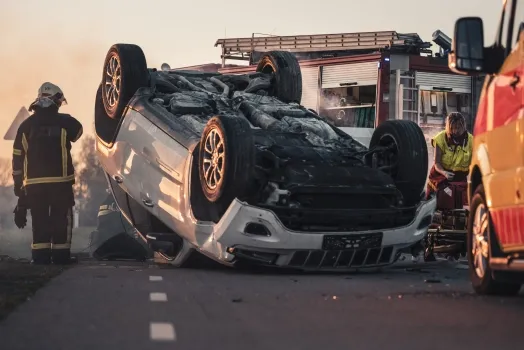 Burning Vehicle Lying on its Roof in the Middle of the Road after Collision.